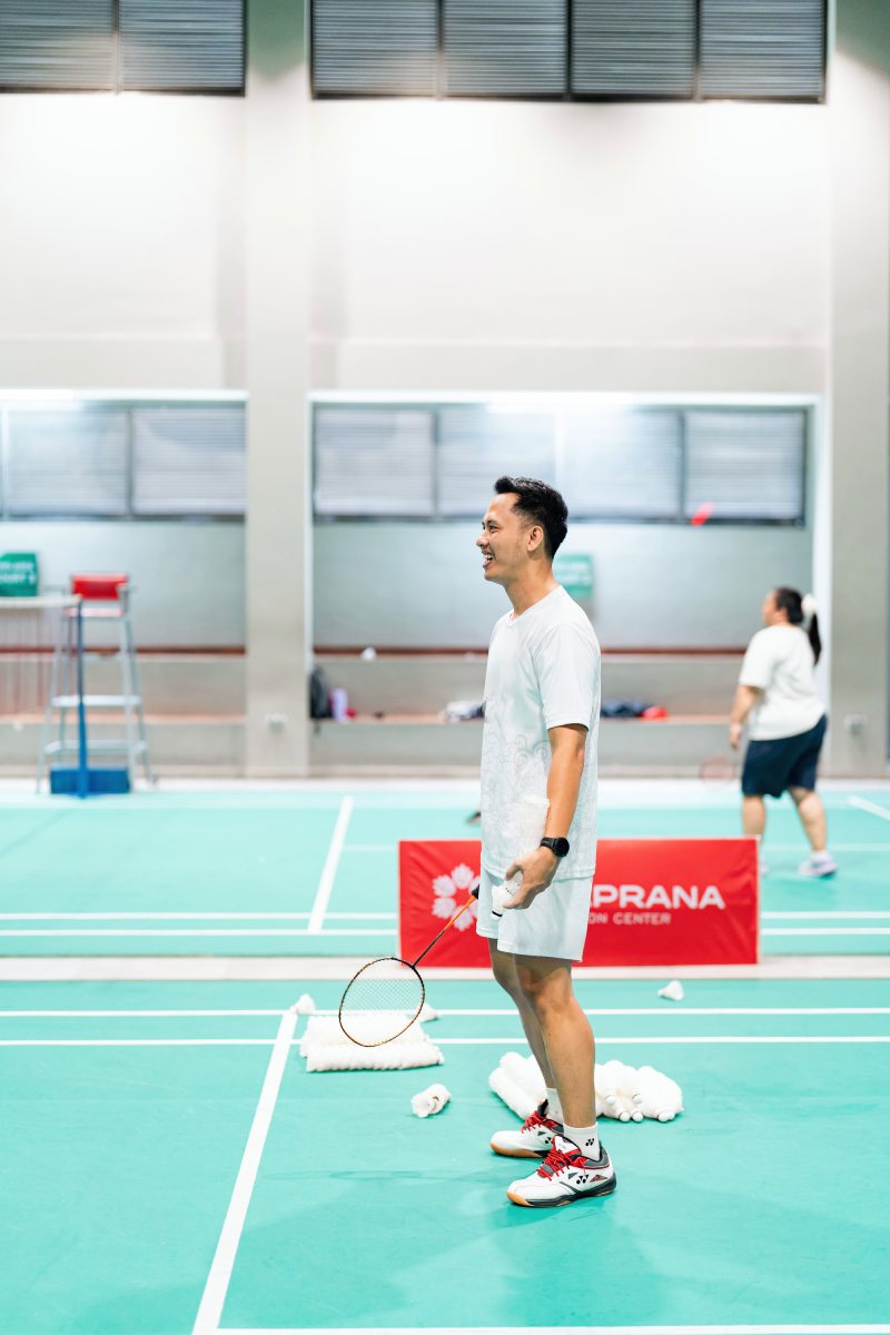Coach Anas training a student during a private badminton lesson at an indoor court in Bali